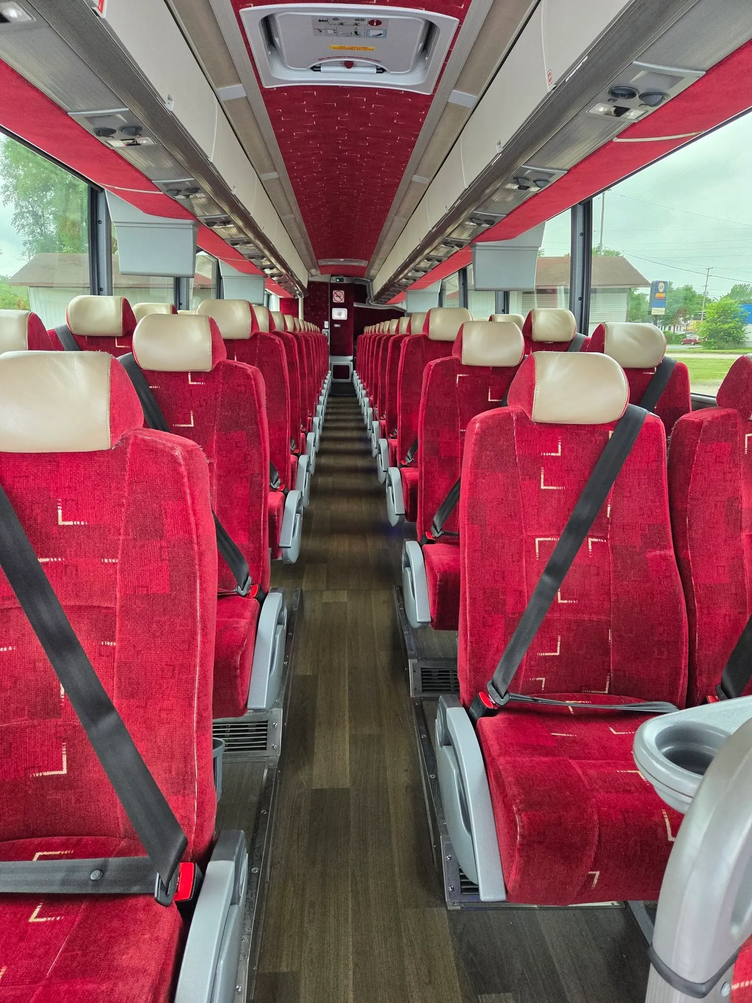 Rows of red fabric seats with seat belts inside a B & W 56 passenger motorcoach