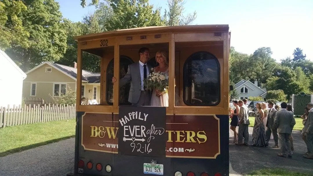 Bride and groom standing on the rear platform of a B & W trolley coach after their ceremony