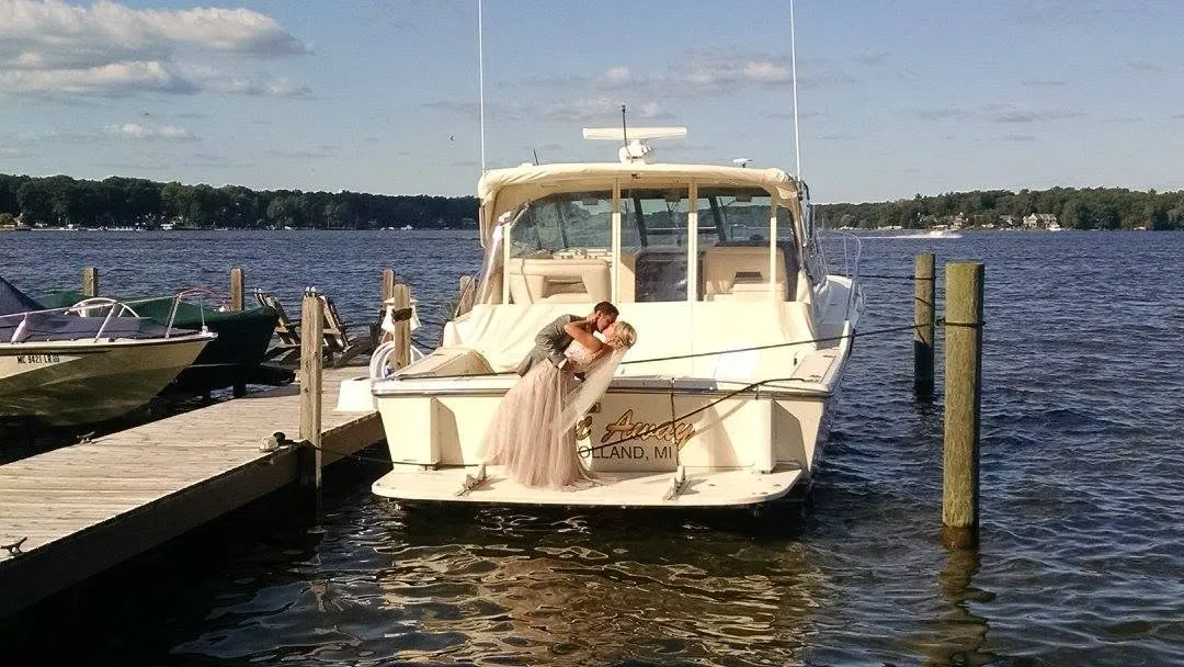 Bride and groom kissing on the back of a boat at a Holland, Michigan dock after a B & W wedding run